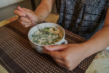 Cold soup name - okroshka, the national dish of the cuisine of Russia and Ukraine. Cold soup with fresh cucumbers, radishes, potato and sausage with yoghurt in bowl.