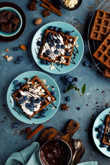 Chocolate belgian waffles with ice cream and fresh blueberry on blue background, top view