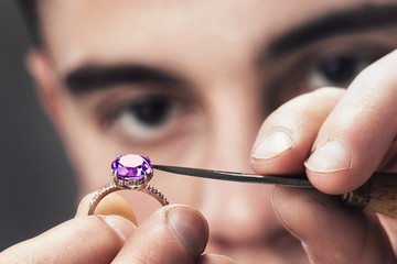 Jewelry master examines the gold ring for defects, close-up - obrazy, fototapety, plakaty