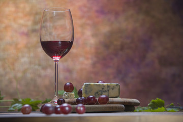 A glass of wine with cheese and grapes