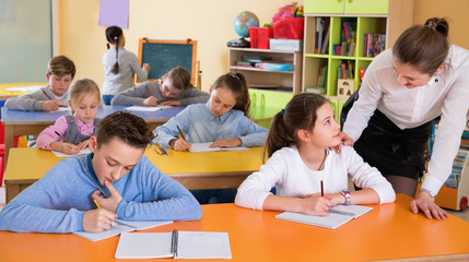 Portrait of young teacher woman at lesson with diligent school kids