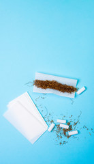 TOBACCO WITH PAPER AND FILTERS ON BLUE BACKGROUND