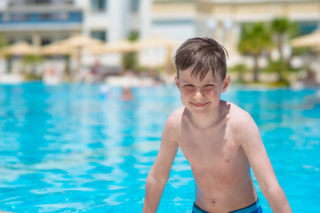 European boy on side of swimming pool at resort on summer.