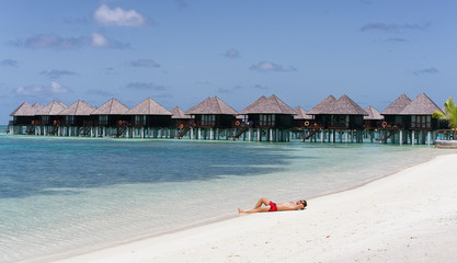 A man lying down in the sand of the beach in a Maldives resort