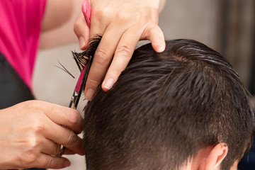 Hairdresser cuts short hair with scissors. Man's haircut.