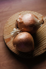 ONIONS ON WOODEN TABLE ILLUMINATED BY WINDOW LIGHT 