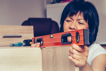 Woman assembling furniture and using leveling tool