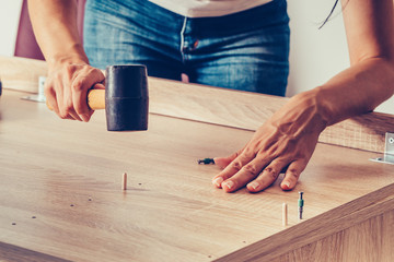 Female hands assembling furniture and using a rubber hammer