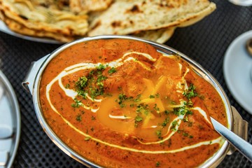Bowl with chicken tikka masala and naan bread.