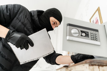 The thief opens the electronic safe. The burglar commits a crime in Luxury apartment with stucco....