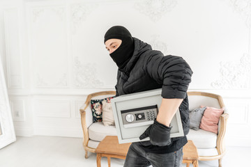 The burglar commits a crime in Luxury apartment with stucco. Thief with black balaclava stealing...