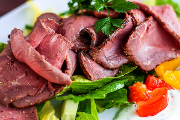 Sliced roastbeef on vegetable salad.