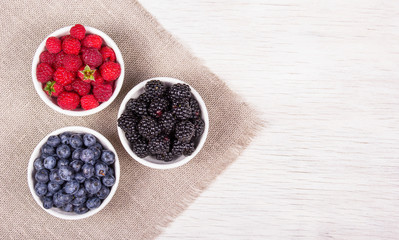 Blueberries, raspberries and blackberries on white background. Blueberry raspberry blackberry in white bowl.  Copy space. Top view