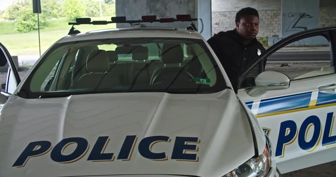 Two police officers getting out of patrol car with flashing lights pointing handguns on thives controlling the robbery scene on city street. Police on duty.