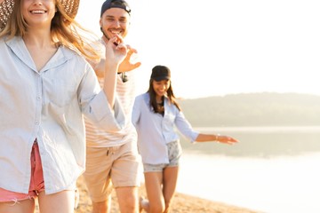 Group of friends having fun running down the beach