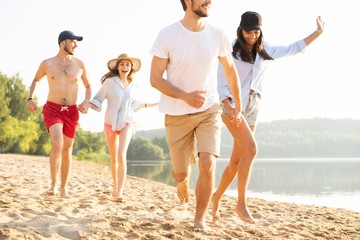 Group of friends having fun running down the beach