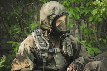 rebel man with gas mask and riffles against a in the forest.