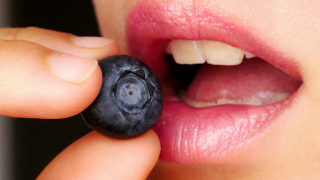 sensual mouth eating a blueberry
