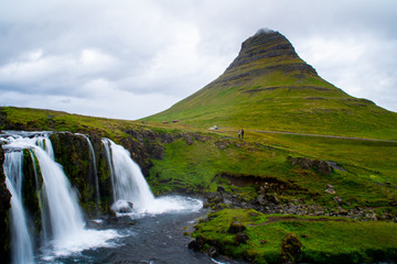 Fototapeta na wymiar Scenic panorama view of long exposure falling water in front of Kirkjufell volcano mountain, the most iconic travel destination location in Iceland. Summer time.