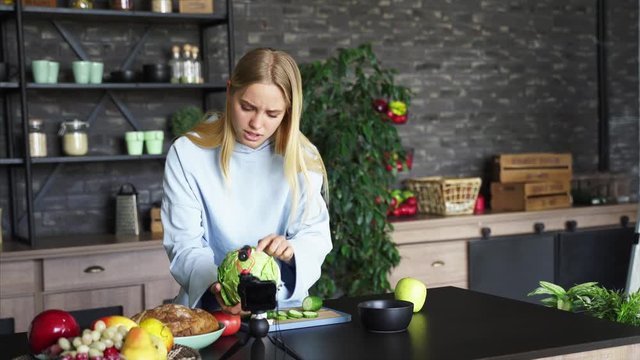 Young beautiful blonde takes on videos as she cooks in the kitchen