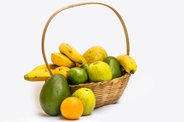 Avocado, papaya, orange, banana, guava and lemon in a basket made of bamboo, on a white background.