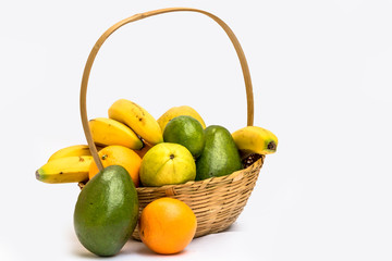 Avocado, papaya, orange, banana, guava and lemon in a basket made of bamboo, on a white background.
