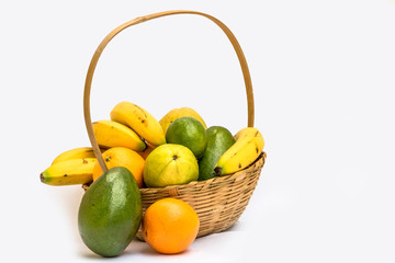 Avocado, papaya, orange, banana, guava and lemon in a basket made of bamboo, on a white background.