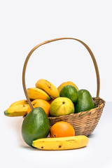 Avocado, papaya, orange, banana, guava and lemon in a basket made of bamboo, on a white background.
