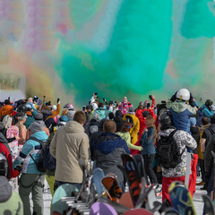 Celebrating winter Holi festival. Colorful powder explosion. Silhouettes of unrecognizable people back to us shooting shows on phones, other gadgets