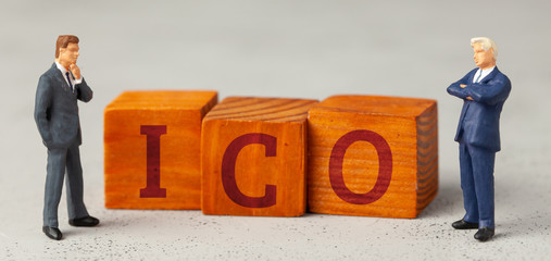 Businessmen and the word ICO and investments on a gray background.