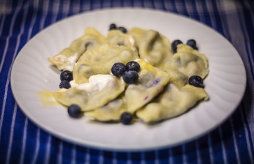 Plate full of Polish pierogi with blueberry filling.