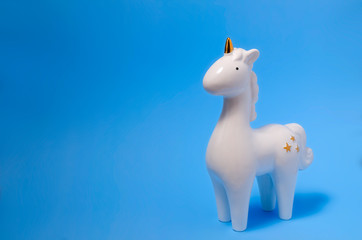 White porcelain unicorn figurine on blue background