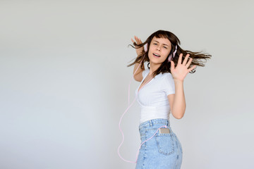 close up photo of a happy brunette with pink headphones in white blouse and denim skirt