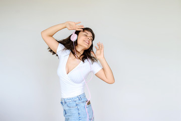Fototapeta premium close up photo of a happy brunette with pink headphones in white blouse and denim skirt