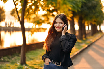 Fashion happy cool smiling girl talking on smartphone in colorful clothes oin th park