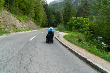 disabled person in an electric wheelchair driving on the street, road