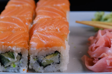 Sushi roll with seafood and soy sauce, wasabi and ginger. Sushi roll with salmon on a black background.