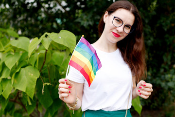 The concept of LGBT rights, the hand holds the LGBT flag, against the backdrop of nature. A young...