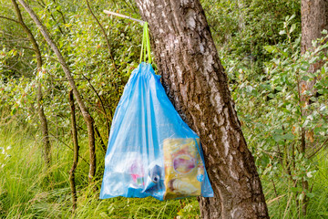 Package with garbage,waste hanging on a tree