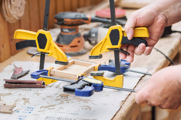 Senior carpenter glueing wooden craft surface and joining with clamps. Woodwork carpenter with...
