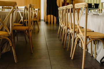 Tables and wooden chairs arranged and decorated in a wedding hall of a hotel