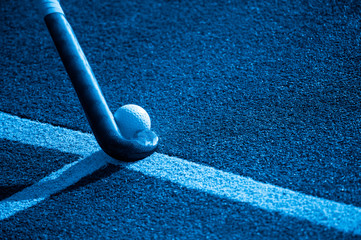 Field Hockey Stick and Ball on fake Grass With Copy Space. Blue filter.