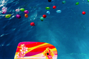 Colorful plastic water balloons floating in a pool to play on vacation to cool off.