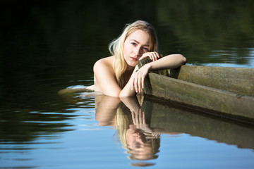 beautiful young woman resting after a swim, holding the edge of a boat