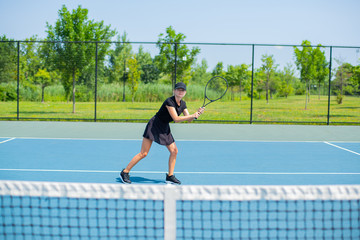 Young sports woman playing tennis on the blue tennis court
