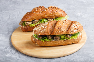 Sprats sandwiches with lettuce and cream cheese on wooden board on a gray concrete background.