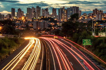 Trail of light caused by vehicular traffic in SP-294, Comandante Joao Ribeiro Barros Highway with buildings from downtown in the background, in Marília, during a late afternoon.