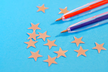 Red and blue fountain pens lie next to the silver stars on a blue background. The problem of brexit. Grade system at school. Ratings and comparisons