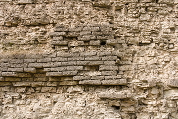 The texture of the broken fortress wall of hand-crafted bricks of gray limestone. Historical stonework of the Varangian fortresses