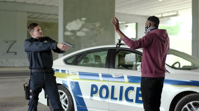 Angry policeman with a pistol standing with a robber in handcuffs arrest bad guy crime danger dangerous gangster gun illegal law pistol teamwork safety security emergency slow motion